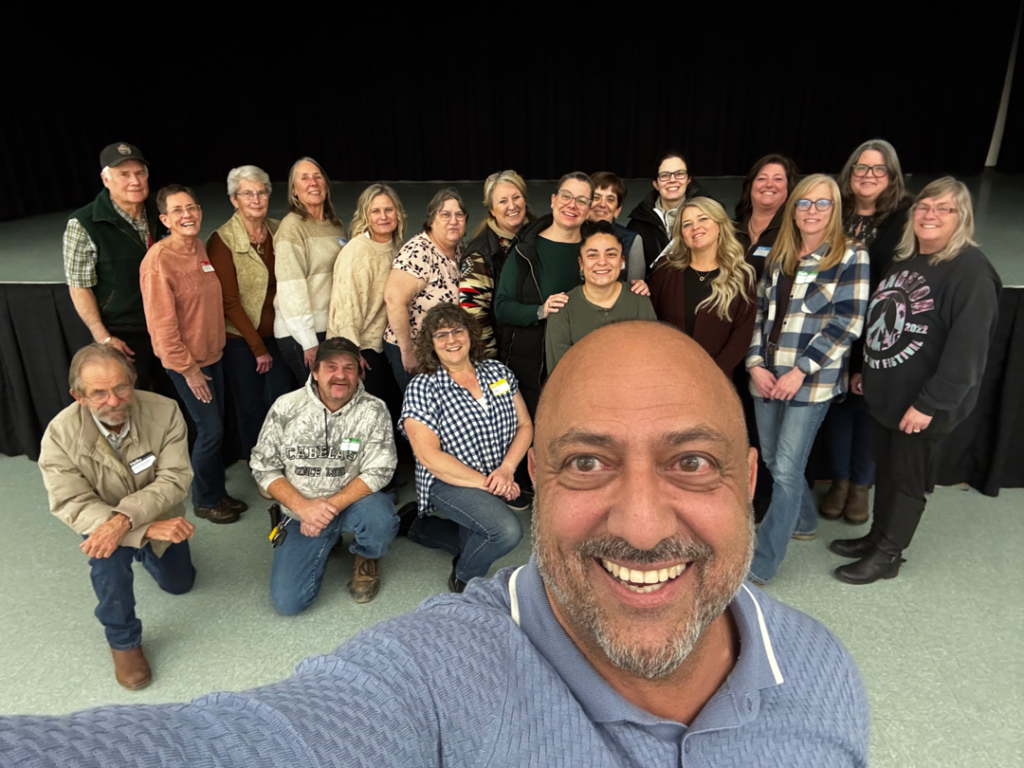 Group of people posing together indoors for a You Make The Difference Alberta event, with one person taking a selfie in front of the group
